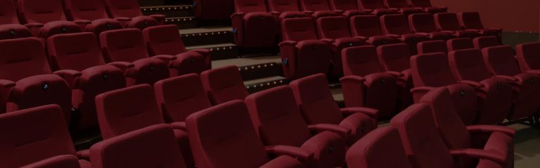 A dimly-lit section of red cinema-style seating